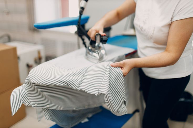 Repassage manuel d'une chemise rayée dans l'atelier Colblanc · savoir-faire artisanal