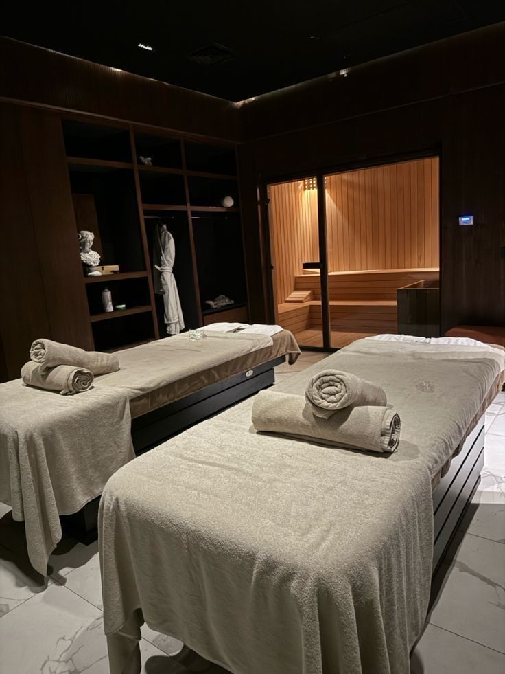 Cabine de spa avec tables de massage, serviettes roulées et sauna · pressing salon et spa Colblanc