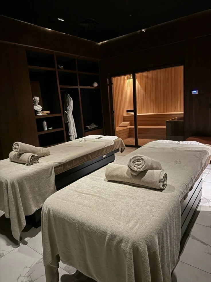 Cabine de spa avec tables de massage, serviettes roulées et sauna · pressing salon et spa Colblanc